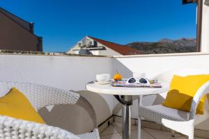 mały stolik na balkonie z żółtymi poduszkami w obiekcie Villa Erna w Dubrowniku