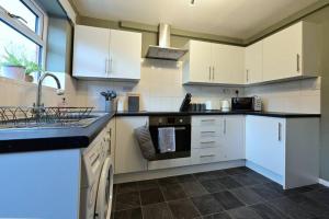 uma cozinha com armários brancos e bancadas pretas em Reduced rates for weekly, monthly and longer stays em Durham