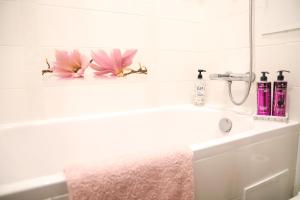 a bathroom sink with two pink flowers on it at Magnolia apartment in Liepāja