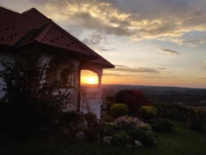 ein Haus auf einem Hügel mit Sonnenuntergang im Hintergrund in der Unterkunft Villa Lotus in Štrigova