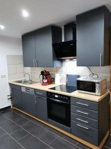 a kitchen with black cabinets and a microwave at Ferienwohnung -kiefer in Hillscheid