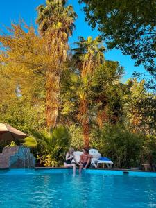 Dos personas sentadas en la piscina de un complejo en Barros Wellness & Spa Resort Boutique, en Los Andes