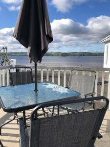 un parasol, une table et des chaises sur le balcon dans l'établissement Séjour, Flèche du fjord, vue Saguenay, Mont Valin, à Saint-Fulgence