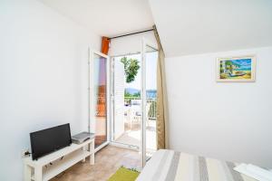 a bedroom with a tv and a sliding glass door at Apartments Villa Cerjak in Slano