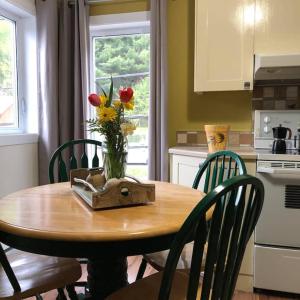 a wooden table with a vase of flowers on it at Séjour, Flèche du fjord, vue Saguenay, Mont Valin in Saint-Fulgence