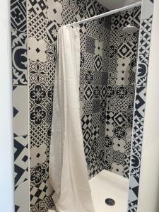 a bathroom with a shower with black and white tiles at Maison de casteljaloux 9 personnes in Casteljaloux