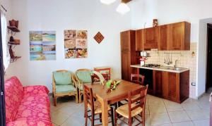 a kitchen and dining room with a table and chairs at B&B Su Frori Arrubiu in Teulada