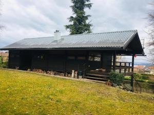 ein schwarzes Haus mit einem Dach auf einem Feld in der Unterkunft Le Fayard vue Lac in Publier