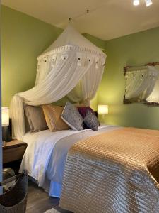 um quarto com uma cama grande e um dossel branco em Suite 2, Flèche du fjord, vue Saguenay, Mont Valin em Saint-Fulgence