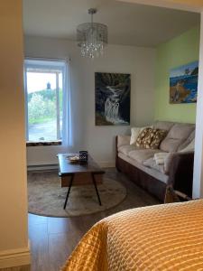 uma sala de estar com um sofá e uma mesa de centro em Suite 2, Flèche du fjord, vue Saguenay, Mont Valin em Saint-Fulgence