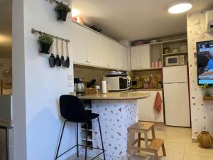 een keuken met een aanrecht met stoelen en een koelkast bij לופט משגע במיקום מרכזי ברמת גן in Ramat Gan