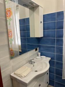 a bathroom with a sink and a mirror and blue tiles at Ventura CasaVacanze in Oliveri