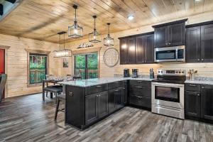 a kitchen with black cabinets and a table in it at New Luxury Vacation Home Cabin in Smoky Gatlinburg - Theater Room in Gatlinburg