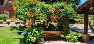 un banc dans un jardin fleuri dans l'établissement Pousada Árvore Da Coruja, à Gramado