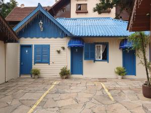 a blue and white house with blue shutters at Pousada Árvore Da Coruja in Gramado