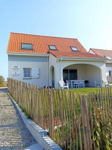 een wit huis met een oranje dak en een hek bij Le Chant des Vagues in Audinghen