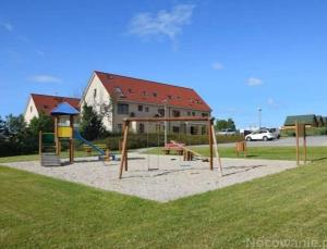 einen Spielplatz vor einem Haus mit Schaukeln in der Unterkunft Apartamenty Wybrzeże Laguna II in Ustronie Morskie