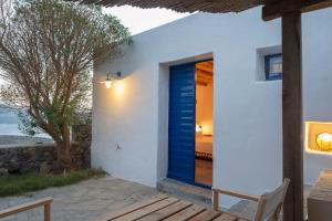 una porta blu sul lato di una casa bianca di Marketos Windmill and Houses a Tripiti