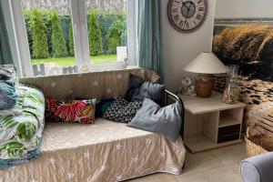 a living room with a couch with pillows and a clock at Apartament Heniokite in Rewa