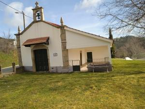 uma pequena igreja branca com uma torre de relógio no topo em Casa da Ribeira em Rabal em Rabal