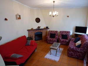 a living room with a red couch and chairs and a fireplace at Casa da Ribeira em Rabal in Rabal