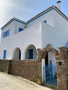 a white house with a blue gate and a stone wall at Psamathe Aegina Apartments in Egina