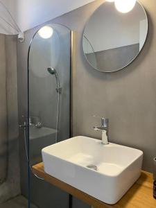 a bathroom with a sink and a mirror and a shower at Psamathe Aegina Apartments in Aegina Town