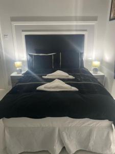 a bedroom with a large black bed with two lamps at THE CRESCENT in Rhyl