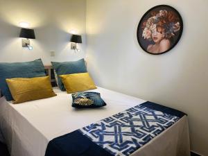 Schlafzimmer mit einem Bett mit blauen und gelben Kissen in der Unterkunft Gabrielle Appartements CANNES in Cannes