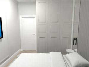 biała sypialnia z łóżkiem i drzwiami w obiekcie Apartament Lux Sopot Monte Cassino w mieście Sopot