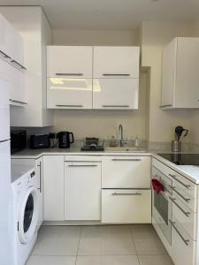 a kitchen with white cabinets and a washer and dryer at Cap d ail 2 pièces proches Monaco et plage in Saint-Antoine