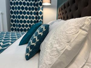 1 cama con sábanas blancas y almohadas azules en Vico Stella Luxury Apartment, Centro storico, Porto Antico Acquario, en Génova
