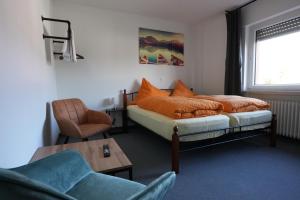 a bedroom with a bed and a chair at Pension Christine in Neu-Anspach