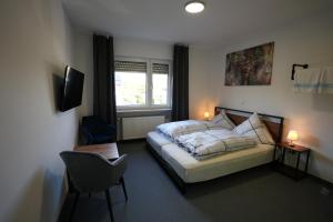 a bedroom with a bed and a chair and a window at Pension Christine in Neu-Anspach