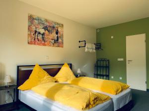 Pension Christine في Neu-Anspach: سرير والمخدات صفراء ولوحة على الحائط