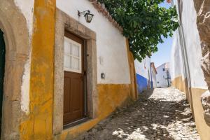 an alley with a brown door on a building at Ana's House in Óbidos