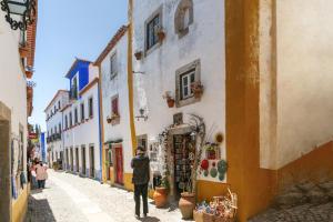 a man walking down a street in an alley at Ana's House in Óbidos +9 photos