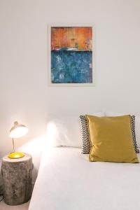 a white bed with a yellow pillow and a painting at Ana's House in Óbidos