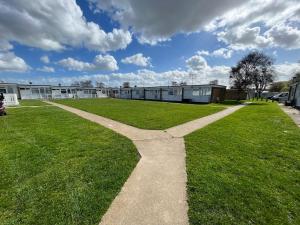 a large grassy field with a building in the background at 88, Belle Aire, Hemsby - Two bed chalet, sleeps 5, bed linen and towels included - pet friendly in Great Yarmouth