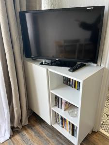a television on a white entertainment stand with dvds at 88, Belle Aire, Hemsby - Two bed chalet, sleeps 5, bed linen and towels included - pet friendly in Great Yarmouth