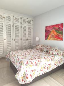 ein weißes Schlafzimmer mit einem Bett mit Blumenbettdecke in der Unterkunft El Mirador Altos de Santa Ana in Córdoba