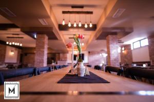 une longue table dans un restaurant avec des fleurs dans des vases dans l'établissement Martini Restaurant & Cazare, à Sebeşel