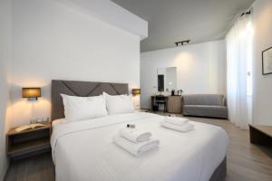 una camera da letto con un grande letto bianco con asciugamani di AMALPHI Corfu City Living a Città di Corfù