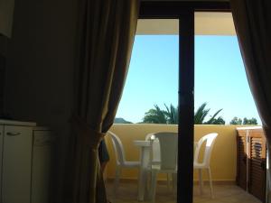 una camera con tavolo, sedie e finestra di Golfo di Marinella stupendo bilocale vista mare a Marinella