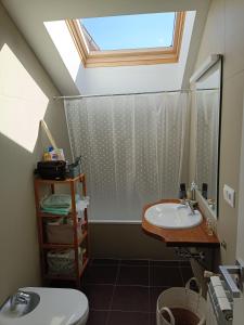 a bathroom with a toilet and a sink with a skylight at Dúplex en Comillas in Comillas
