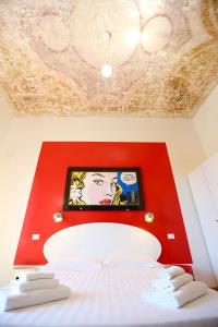 Zimmer mit einer roten Wand mit einem Bett und einem Bild in der Unterkunft KISS ME ROME Luxury Rooms in Rom