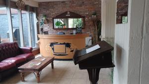 a living room with a piano and a couch at The Renishaw Rooms in Renishaw