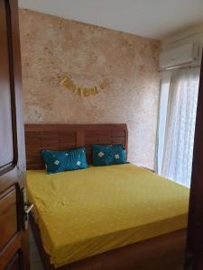 um quarto com uma cama com lençóis amarelos e almofadas azuis em Mousse Diop em Dakar