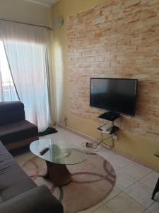 uma sala de estar com um sofá e uma televisão numa parede de tijolos em Mousse Diop em Dakar