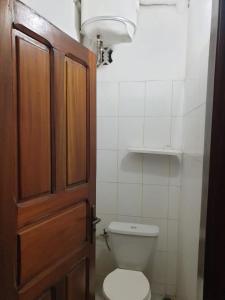 uma casa de banho com um WC e uma porta de madeira em Mousse Diop em Dakar